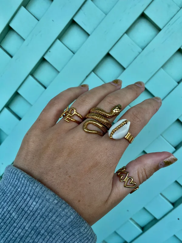 Gold snake ring, cowrie ring and heart ring stacked